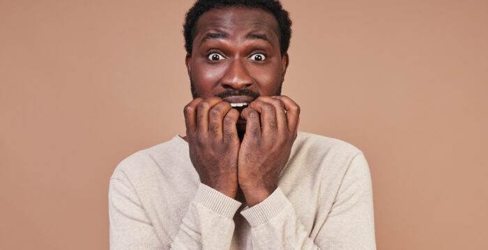 scared young african man casual clothing making face looking camera